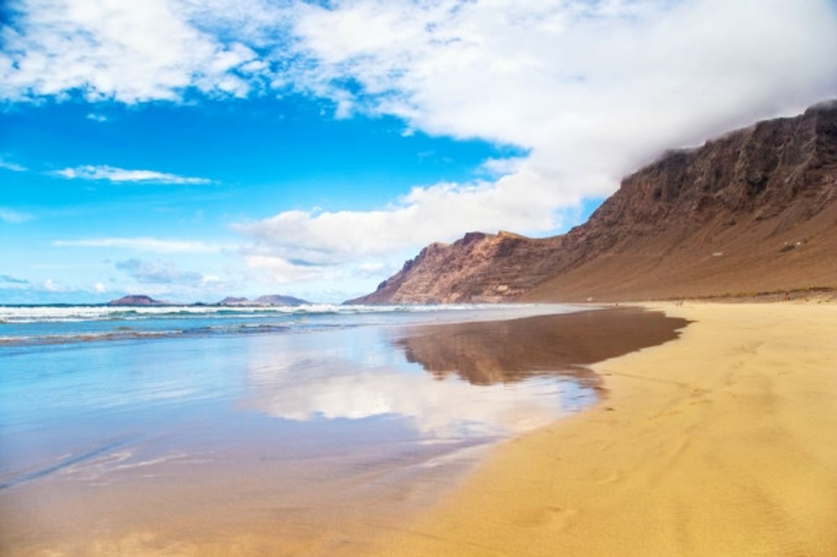 Towering sand dunes and sun-soaked sands of Playa Famara in Lanzarote