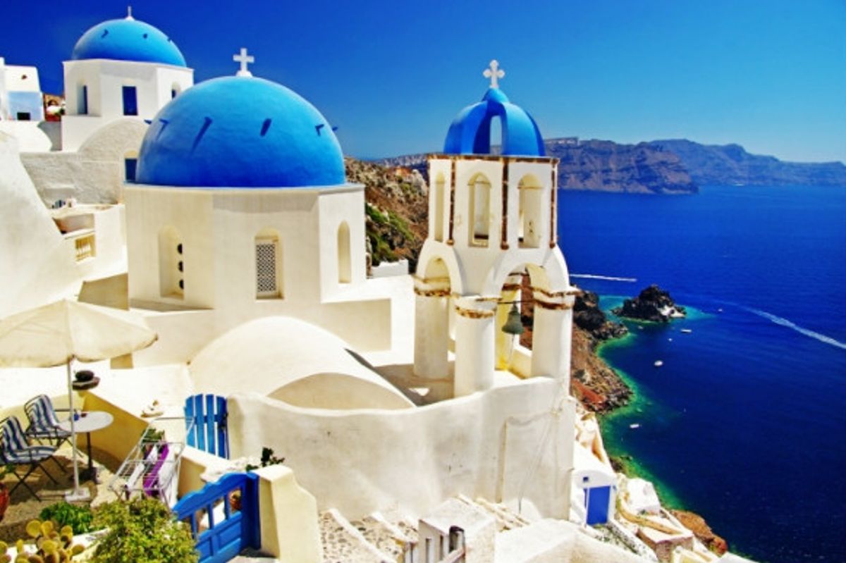 The beautiful Greek blue-domed churches of Caldera and Santorini's breathtaking volcanic backdrop.