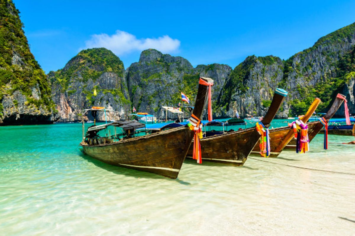 The popular Maya Bay in Thailand with long-tail boats and emerald waters surrounded by tall cliffs
