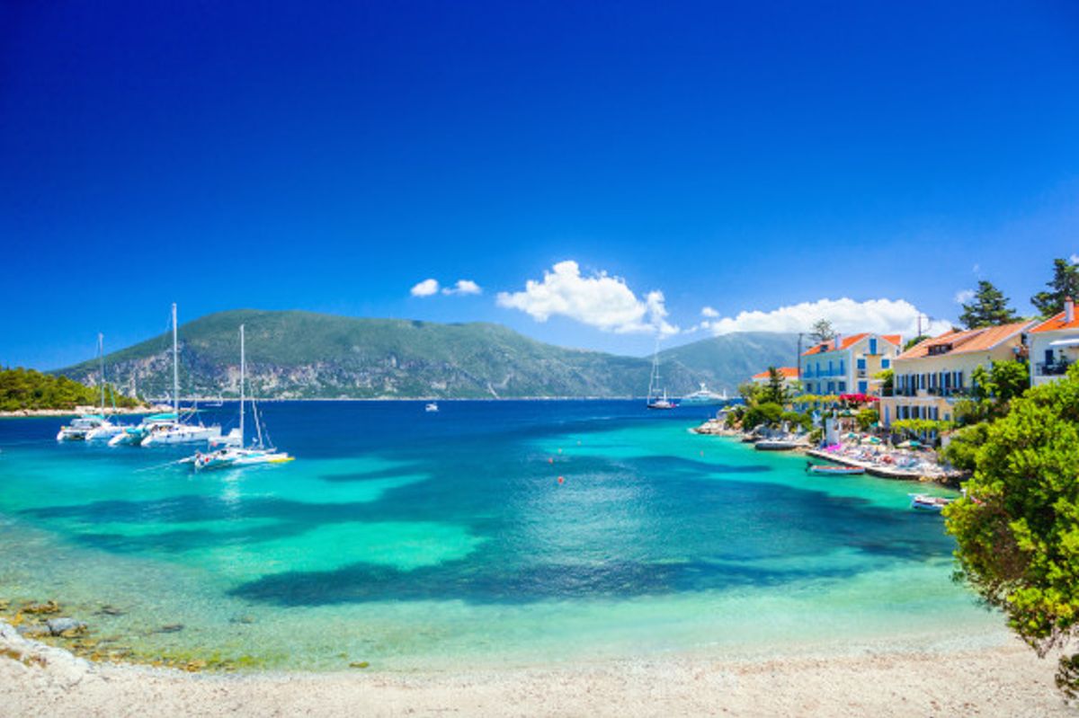 Fiskardo village with emerald coloured waters and surrounding mountain scenery in Kefalonia, Greece