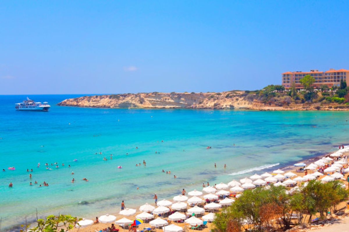 Coral Bay in Paphos, Cyprus with stunning waters and white umbrellas lining the sand