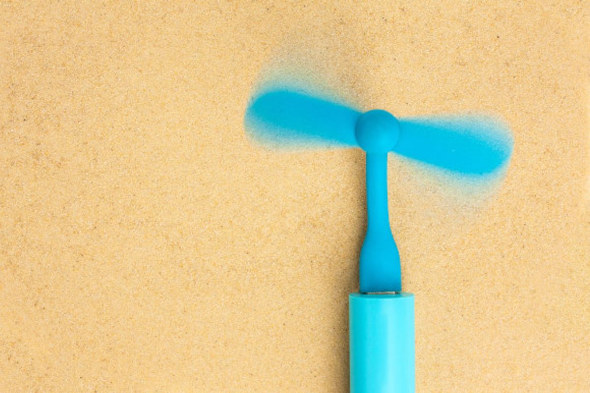 Blue portable fan placed on a beach