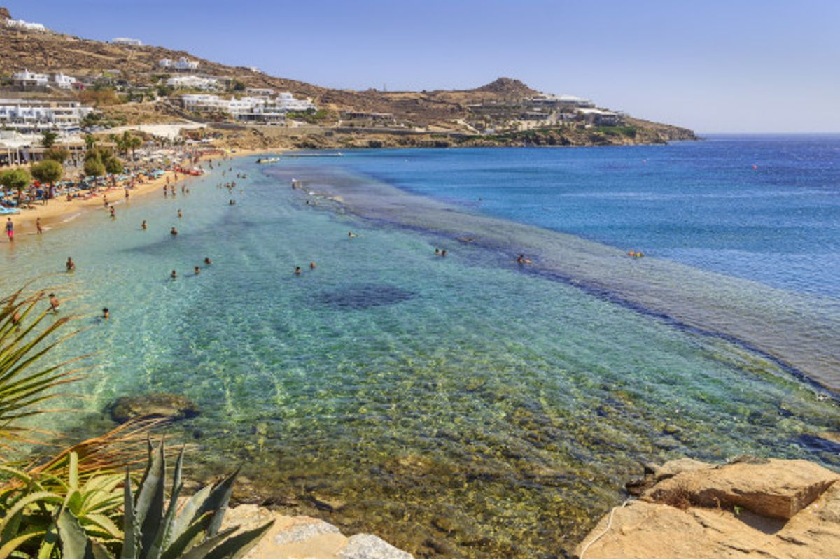 The popular Paradise Beach in Mykonos filled with tourists and backed by traditional whitewashed houses