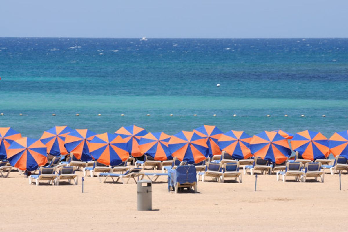 The stunning El Castillo Beach in Fuerteventura filled with umbrellas looking out towards azure waters