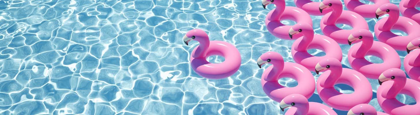 Pink inflatable flamingoes floating on clear blue water