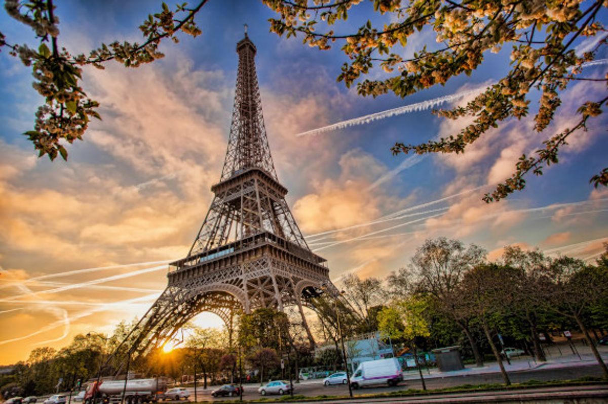 Dusk falling on the Eiffel Tower in Paris with an influx of cars passing by