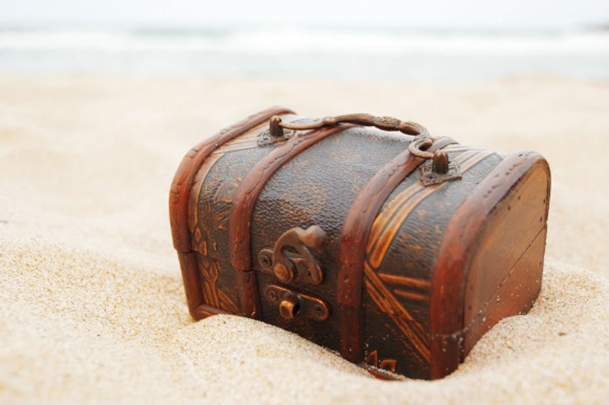 An old treasure chest nestled in the sand on the beach
