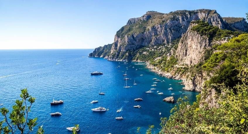 Small boats in the waters floating under the cliffs