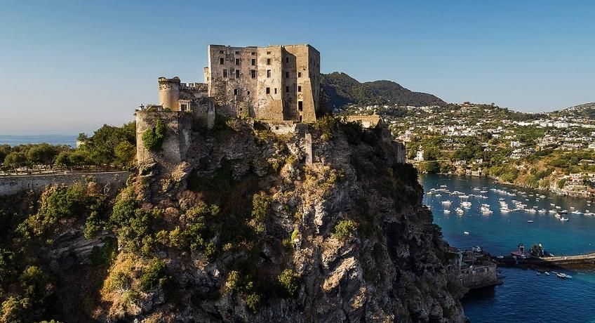 Castle on top of a hill with the ocean in the background