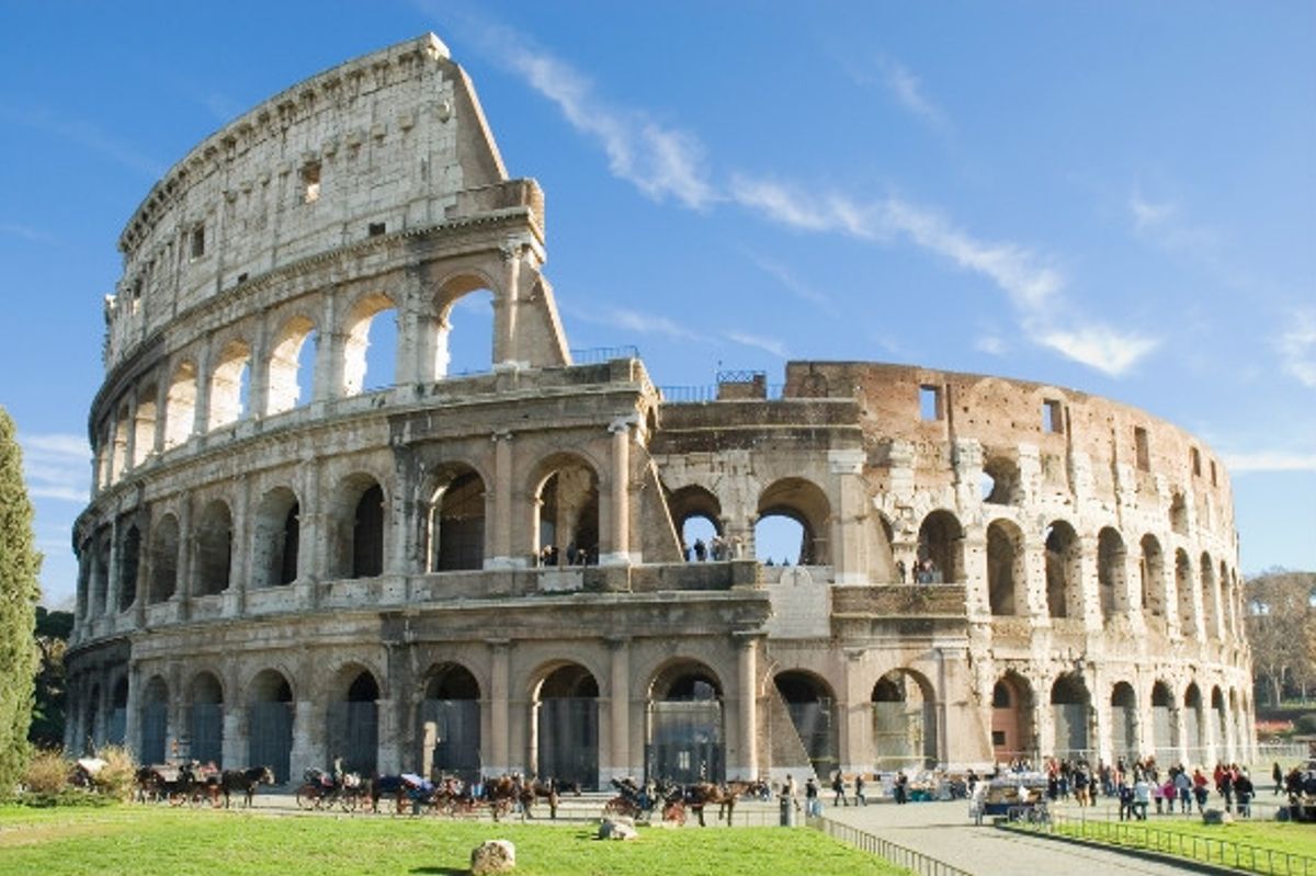 Horse & carriages, and tourists surrounding the ancient Colosseum in Rome, Italy