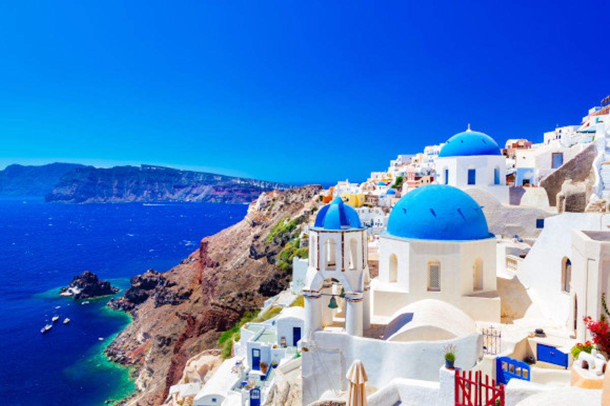 Sun-soaked views over the Iconic Oia in Santorini featuring whitewashed buildings and blue-domed churches