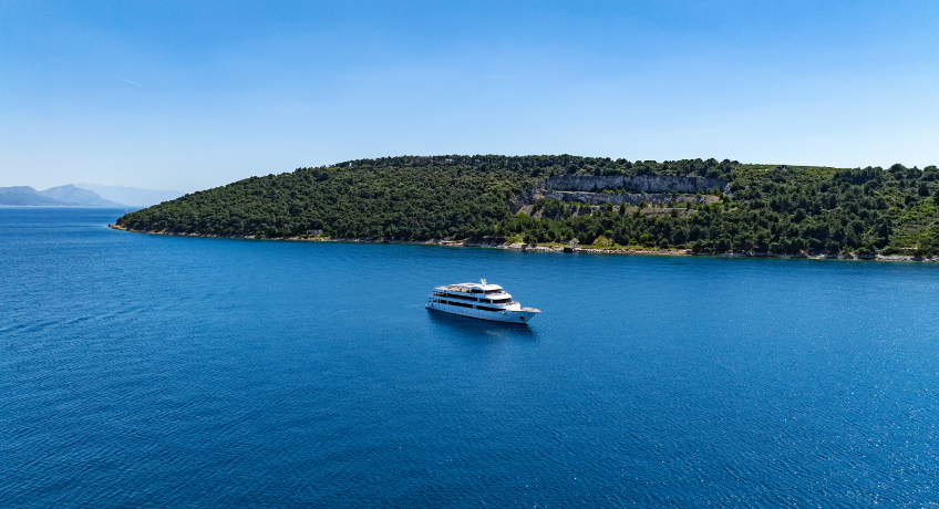 Small ship yacht cruise boat surrounded at wide angle surrounded by crystal blue sea