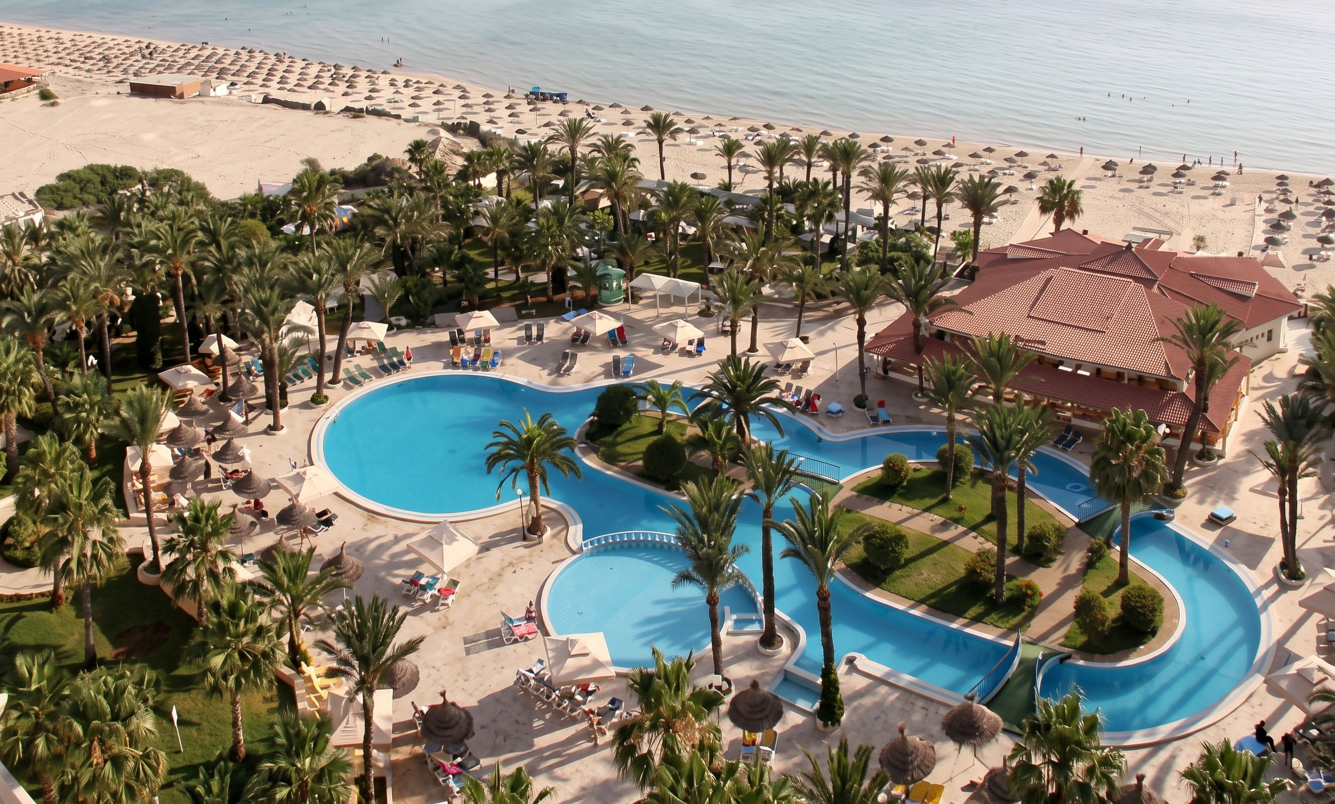 a lagoon pool in the Riadh Palms hotel overlooking a sandy beach