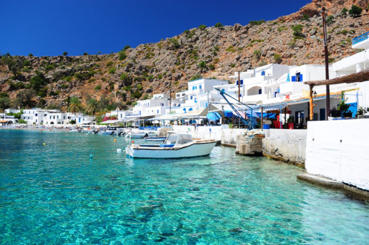 Coastal village in the Greek Island of Crete lined surrounded by traditional whitewashed buildings and beautiful azure waters