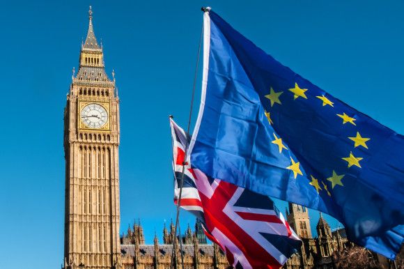 European and UK flag in front of Big Ben with a bright blue sky as the backdrop