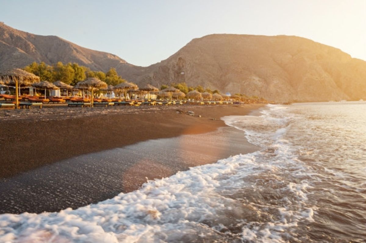 The black sand beach of Perissa during sunrise in Santorini, Greece