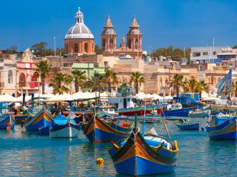 Colourful boats in the sea with traditional buildings in the background