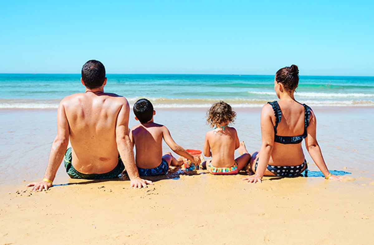Family sitting on a beach with their backs to the camera.