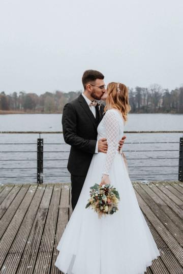 Zweiteiliges Brautkleid online kaufen Brautpaar küsst sich am Wasser