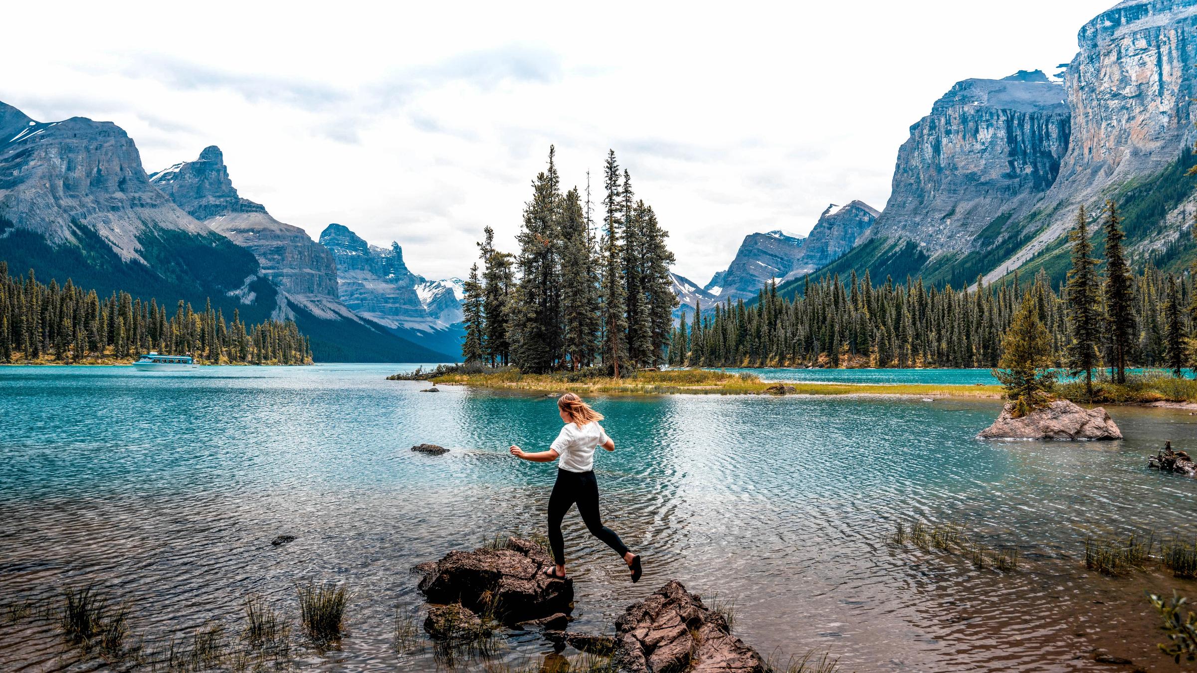 A traveller hops across the rocks at Spirit Island on Maligne Lake, Jasper National Park