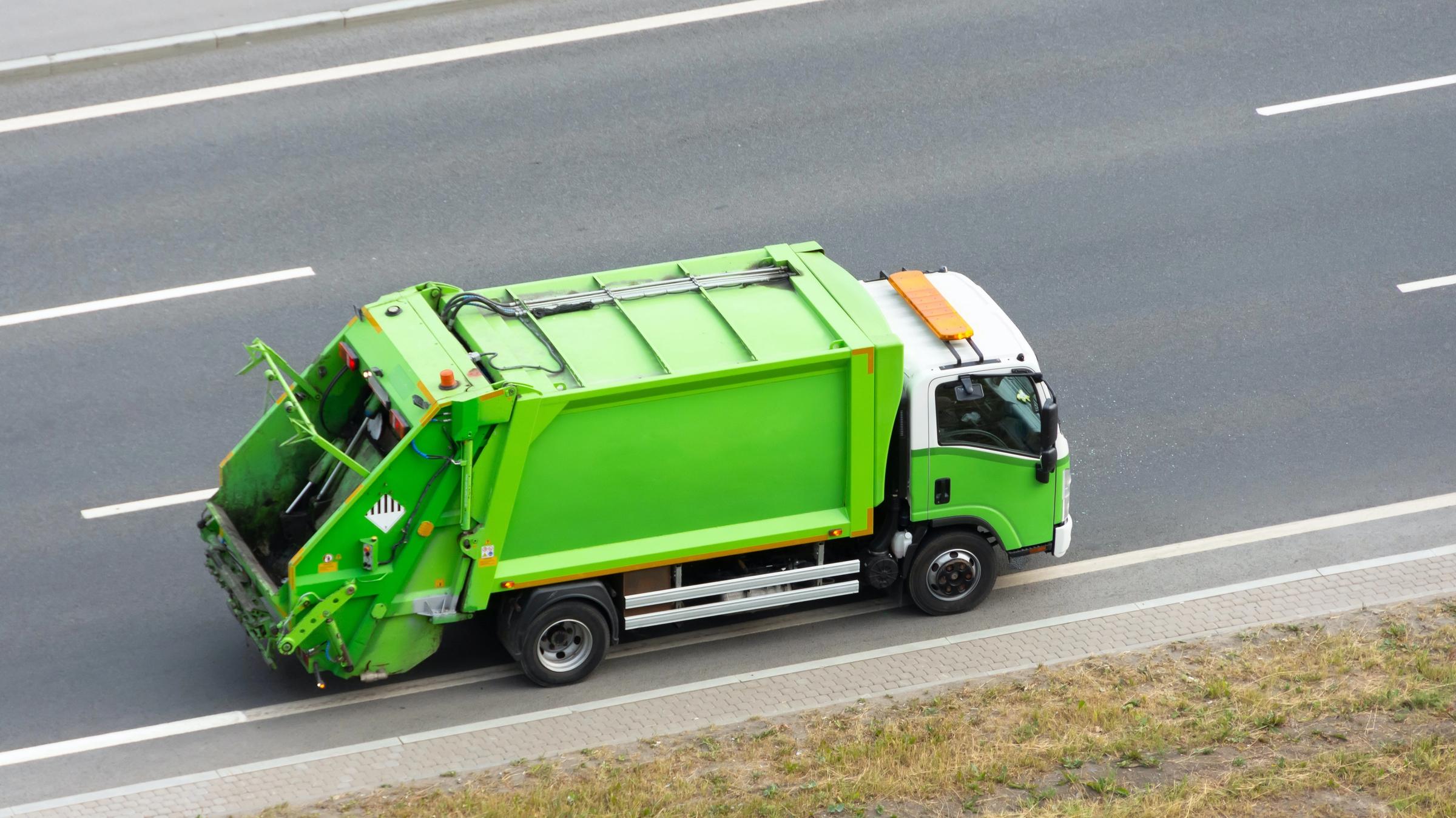 A green waste collection truck on a highway, seen from above
