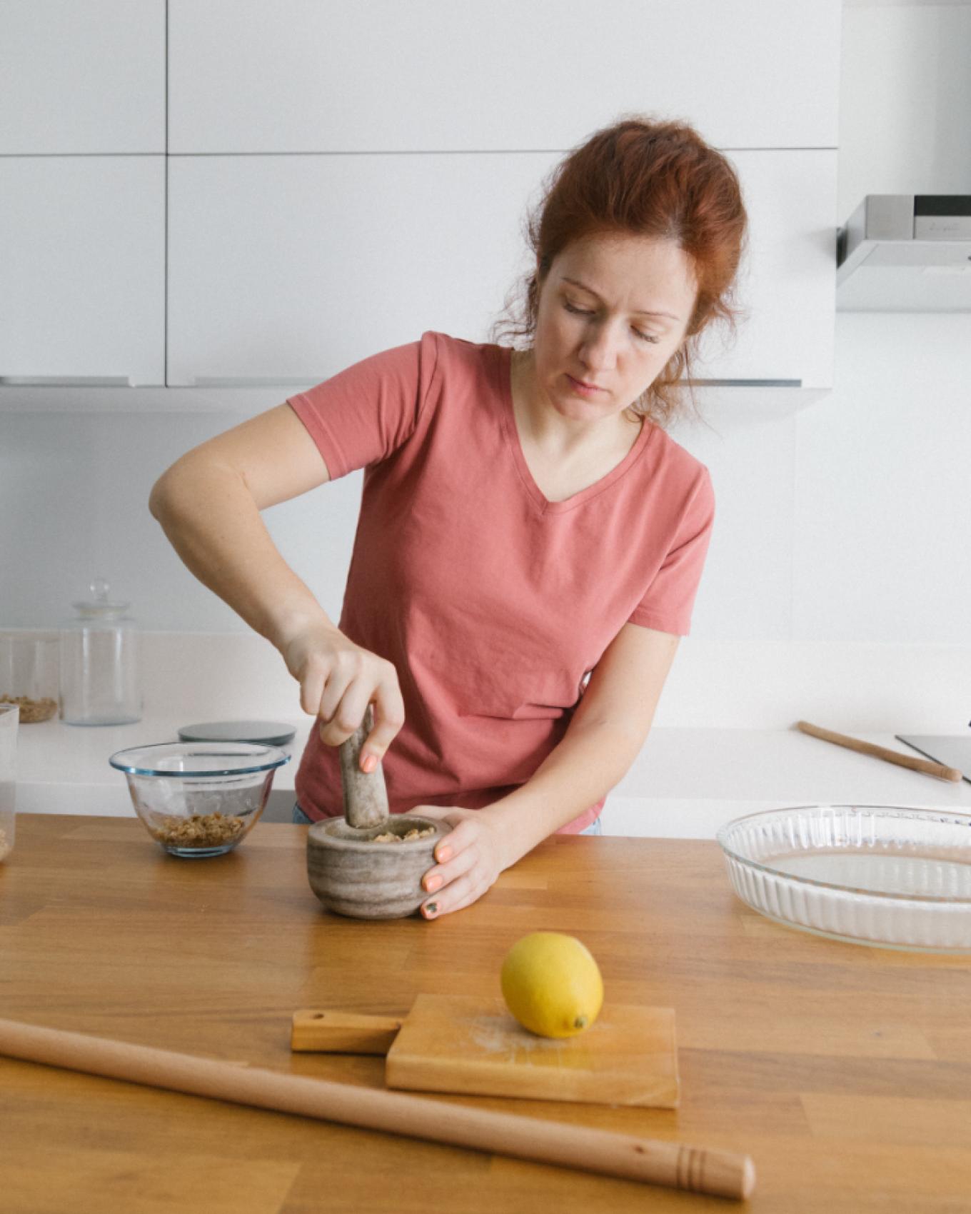 A woman grinding spices at a kitchen counter