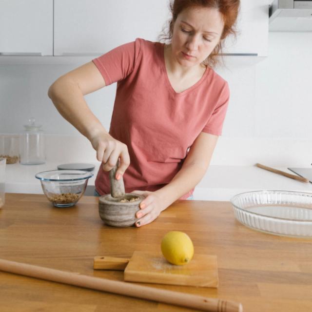 A woman grinding spices at a kitchen counter