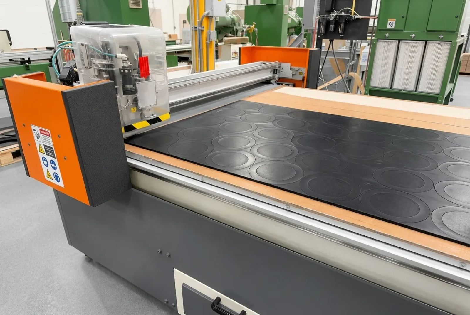 Oscillating-knife flash cutting table with round shapes cut from a black rubber sheet at Cannon Gasket.