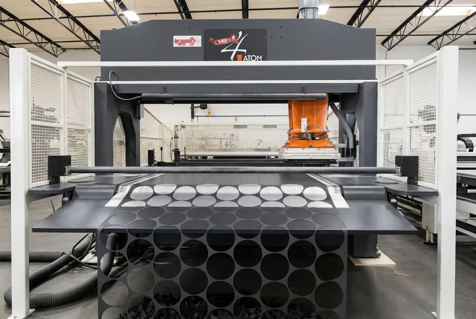 Atom flatbed die-cutting press cutting round rubber blanks from black sheet stock at Cannon Gasket.