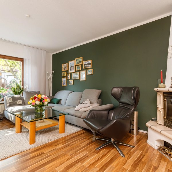 Wohnzimmer Kamin Grüne Akzentwand Parkettboden Gartenzugang