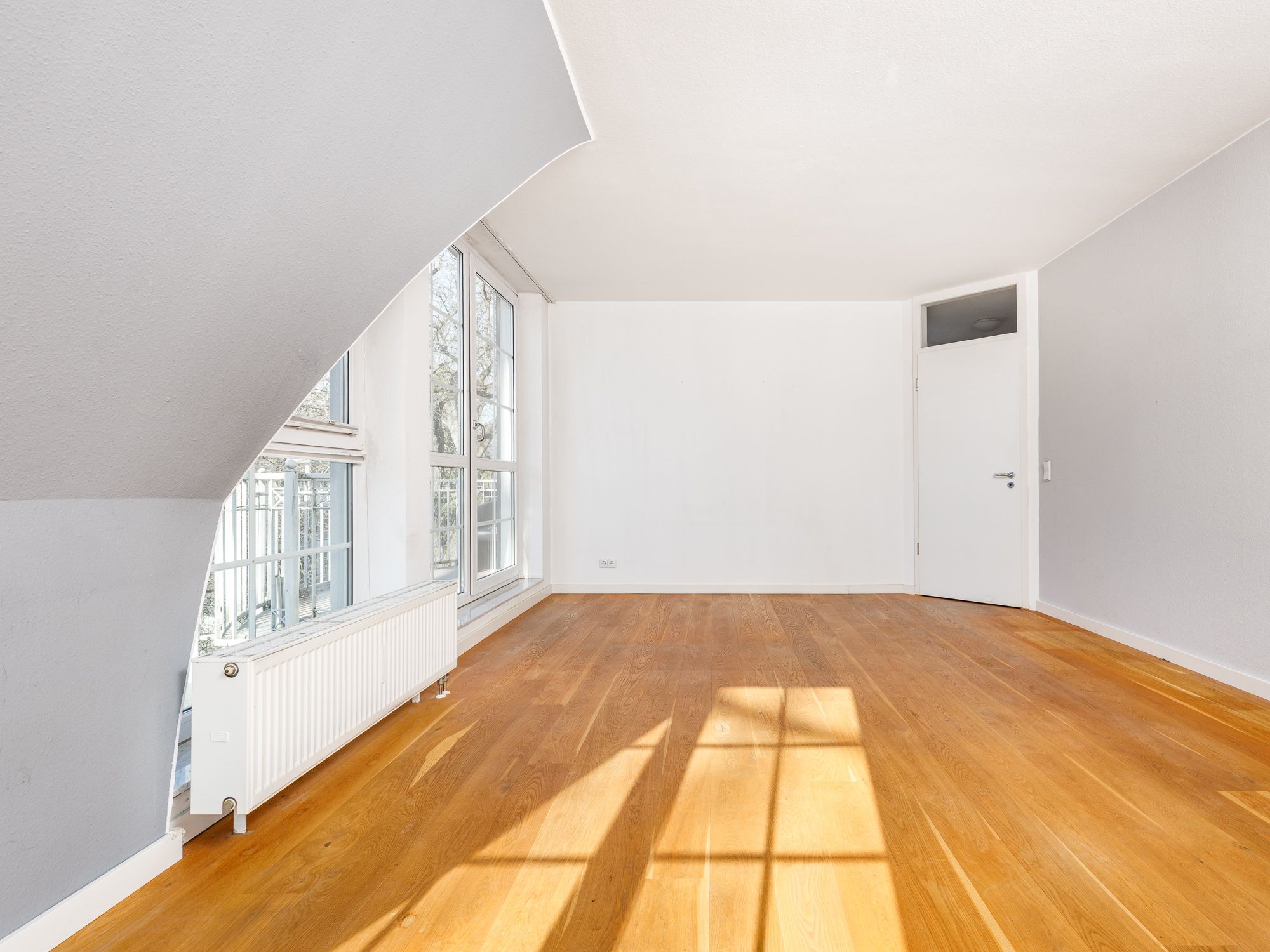 Light-filled bedroom with parquet flooring and floor-to-ceiling windows