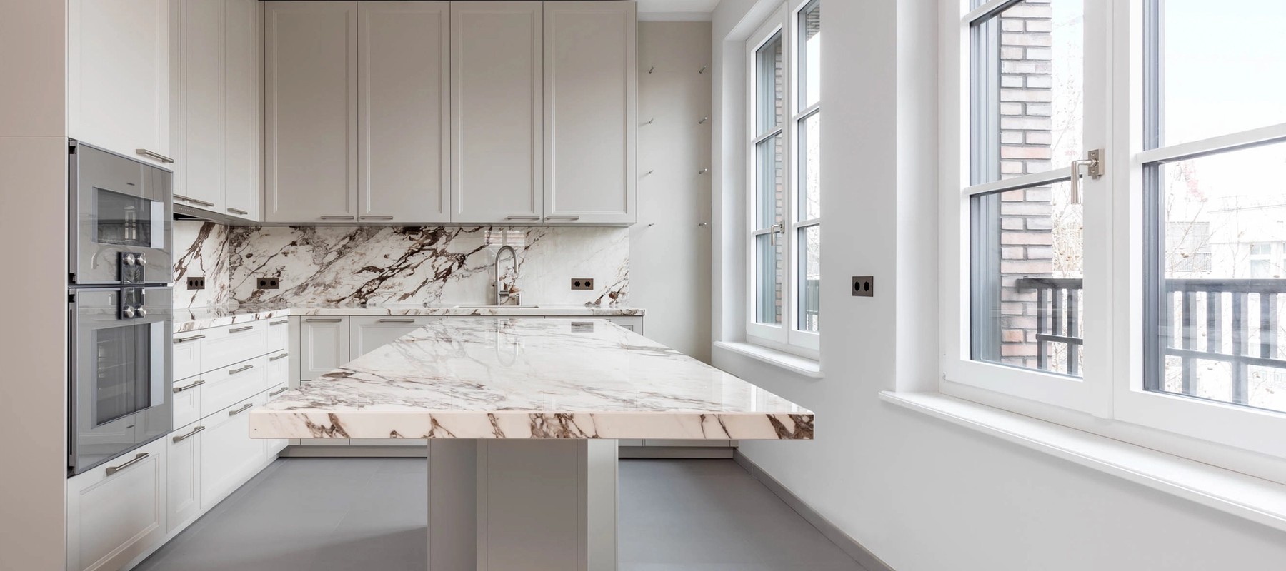 Luxurious fitted kitchen with modern appliances and marble table Luxurious fitted kitchen with modern appliances and marble table