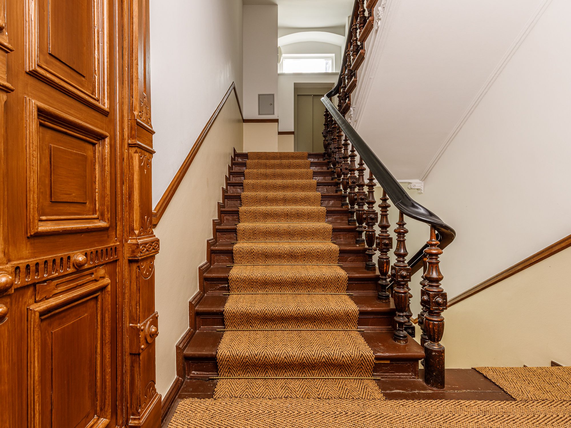 Schönes Treppenhaus mit Sisal-Teppich und historischen Holztüren 