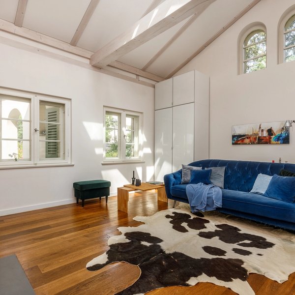 Wohnzimmer mit Sichtbalken Parkettboden und hohen Decken