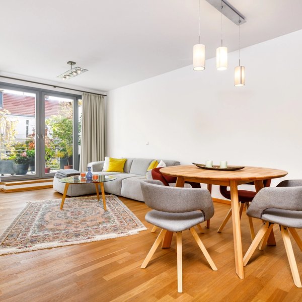 Wohnbereich Rundtisch Sofa Balkonzugang Parkettboden