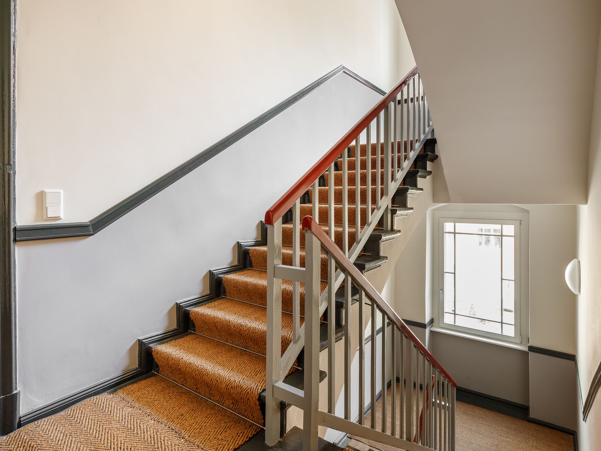 Gepflegetes Treppenhaus mit Sisal-Teppich und Stuck-Ornamenten 