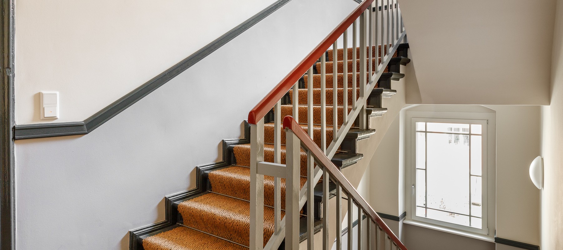 Gepflegetes Treppenhaus mit Sisal-Teppich und Stuck-Ornamenten Gepflegetes Treppenhaus mit Sisal-Teppich und Stuck-Ornamenten