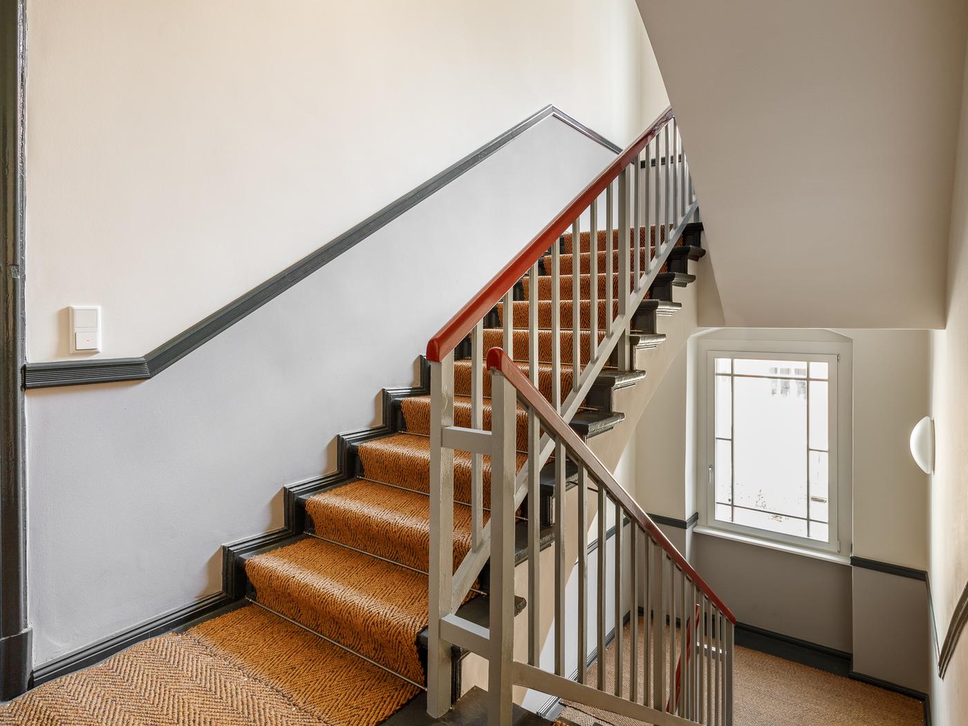 Gepflegetes Treppenhaus mit Sisal-Teppich und Stuck-Ornamenten  Gepflegetes Treppenhaus mit Sisal-Teppich und Stuck-Ornamenten