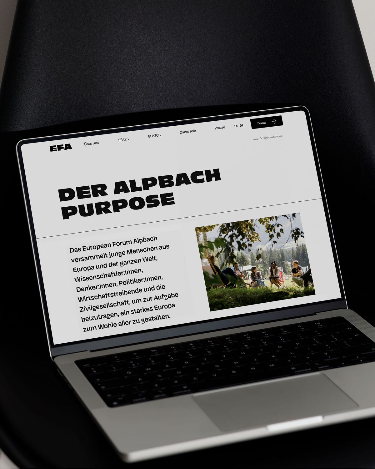 Laptop mit Alpbach Purpose Page auf schwarzem Stuhl
