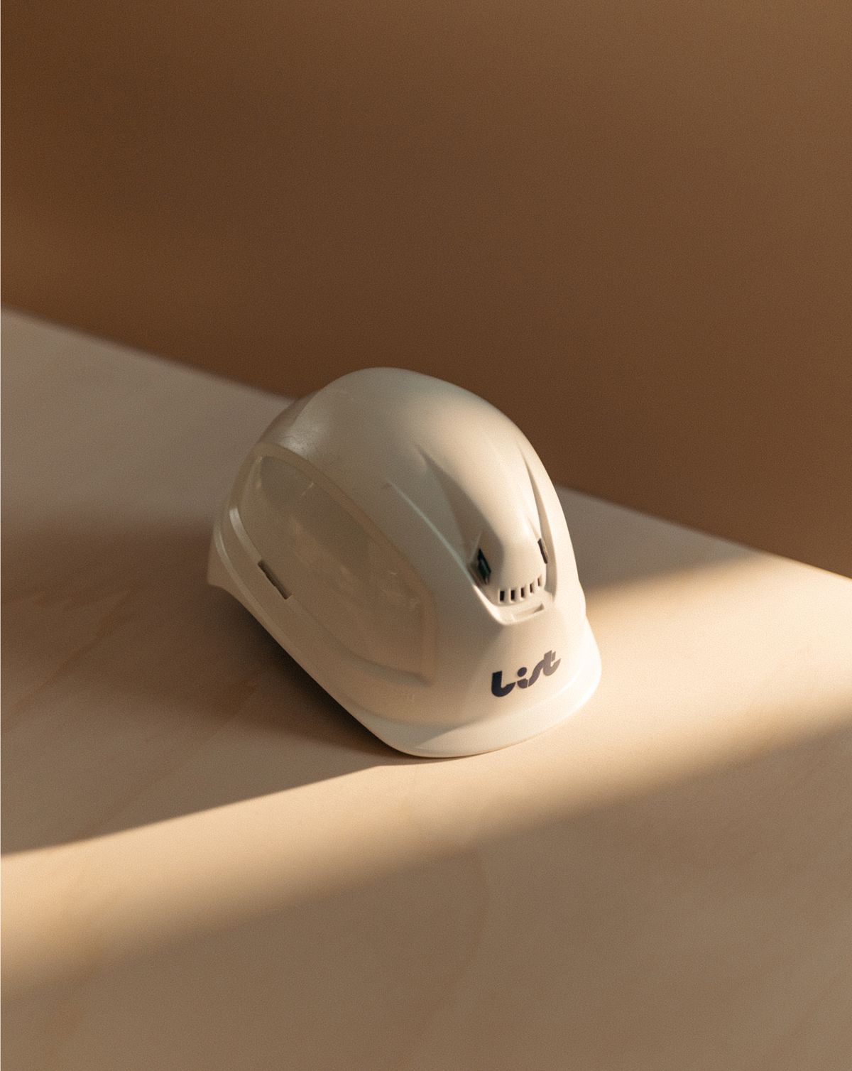 Bauhelm mit List-Logo auf Holzhintergrund