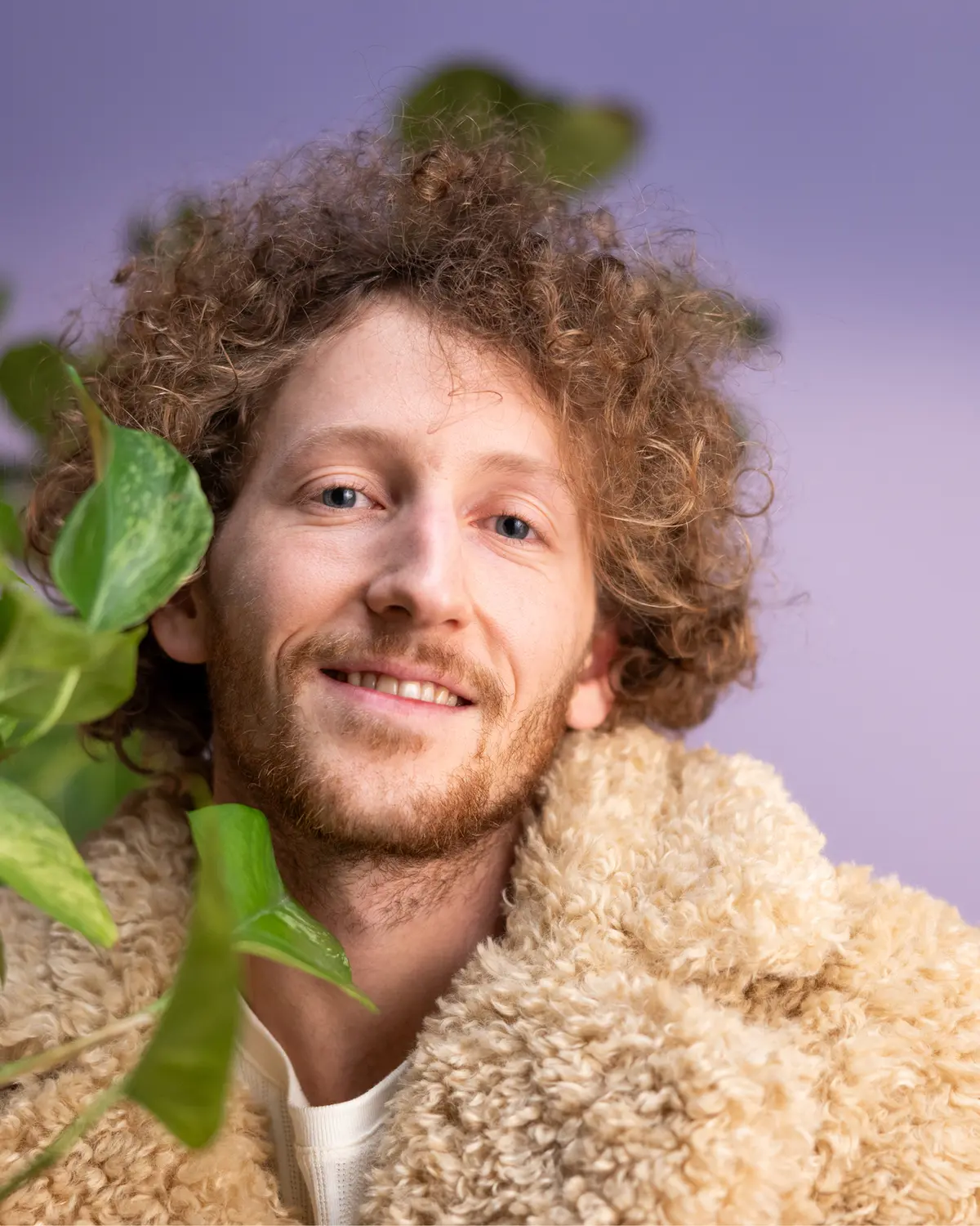 Lächelnder Mann mit grüner Pflanze im Studio