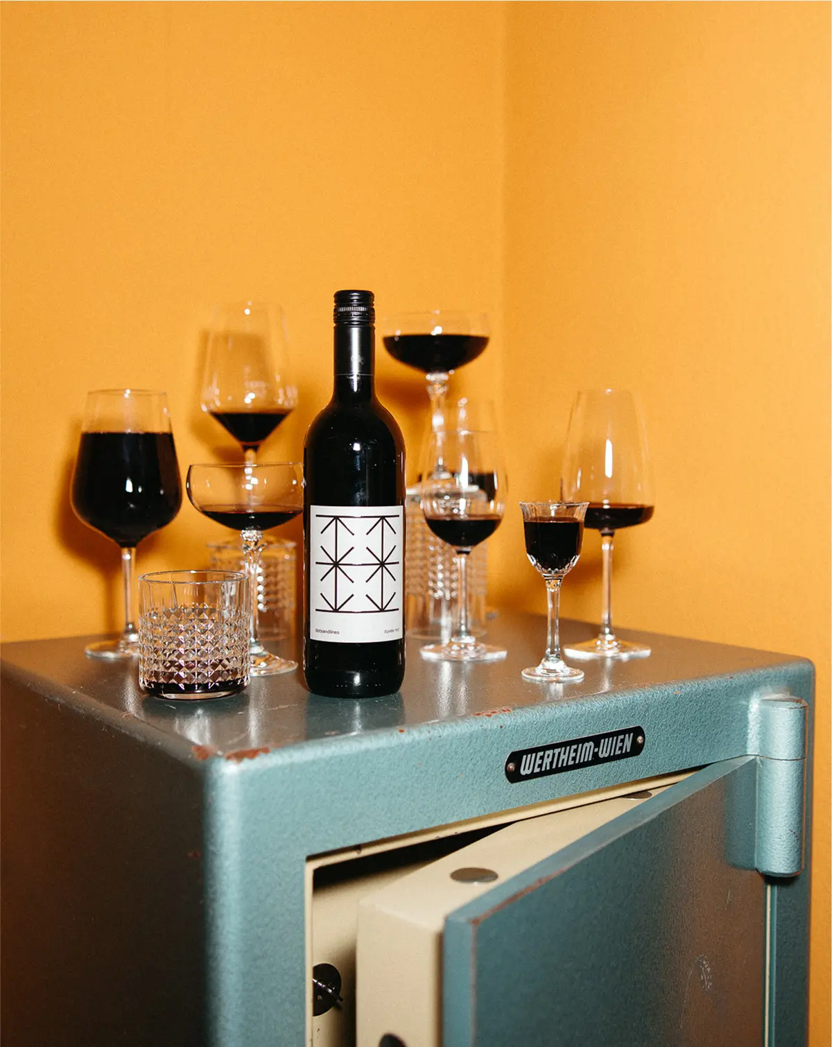 Wine bottle and various filled glasses are on a blue counter