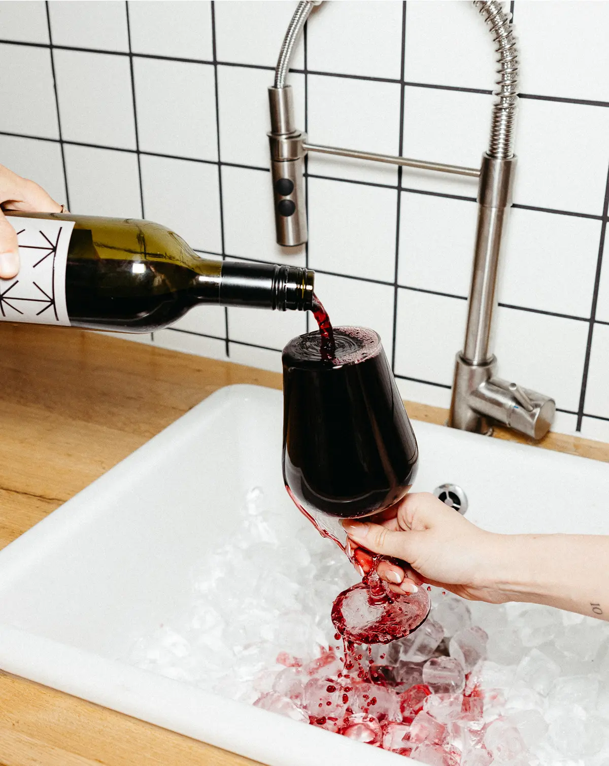 Wine glass is being overfilled over the sink