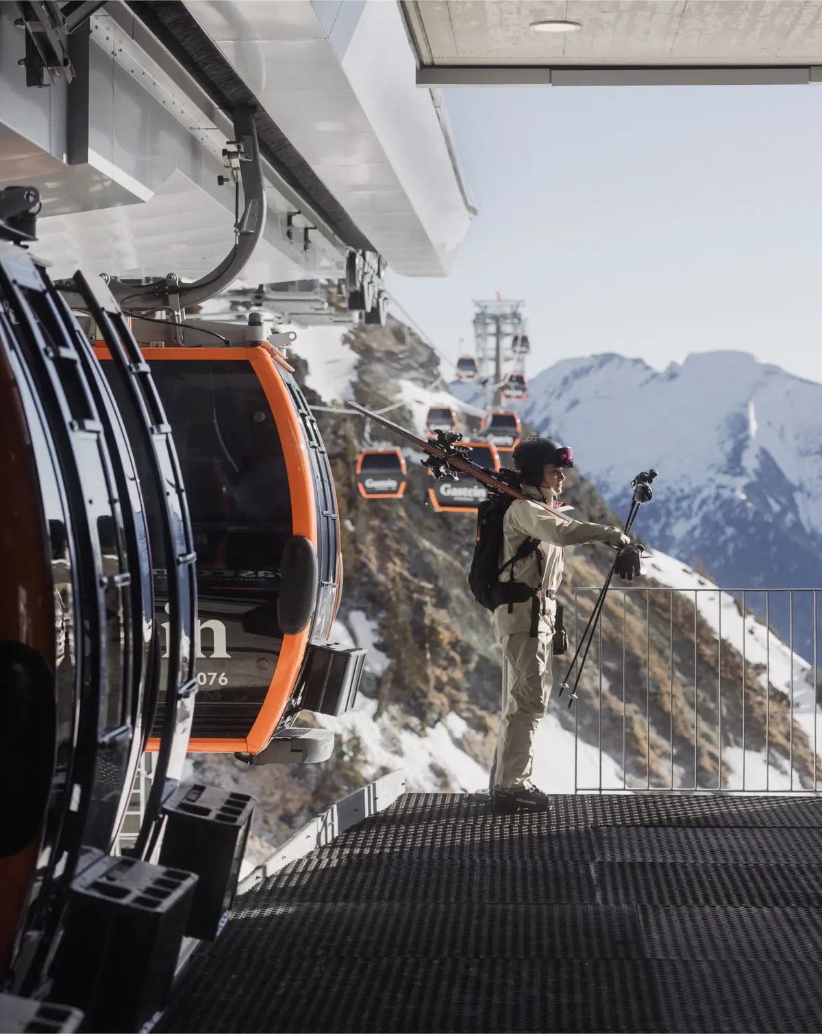 Person steigt mit Ski aus Gondel aus vor Panorama