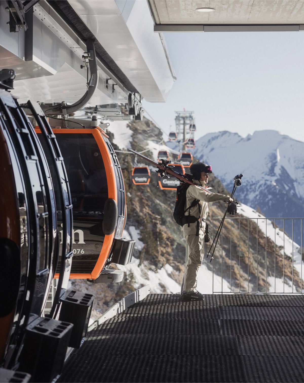 Person steigt mit Ski aus Gondel aus vor Panorama