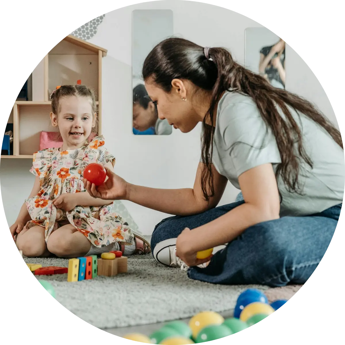 Educator playing with a young girl on a playroom floor