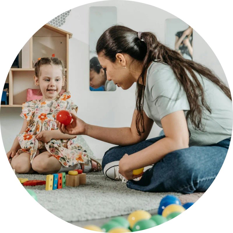 Educator playing with a young girl on a playroom floor