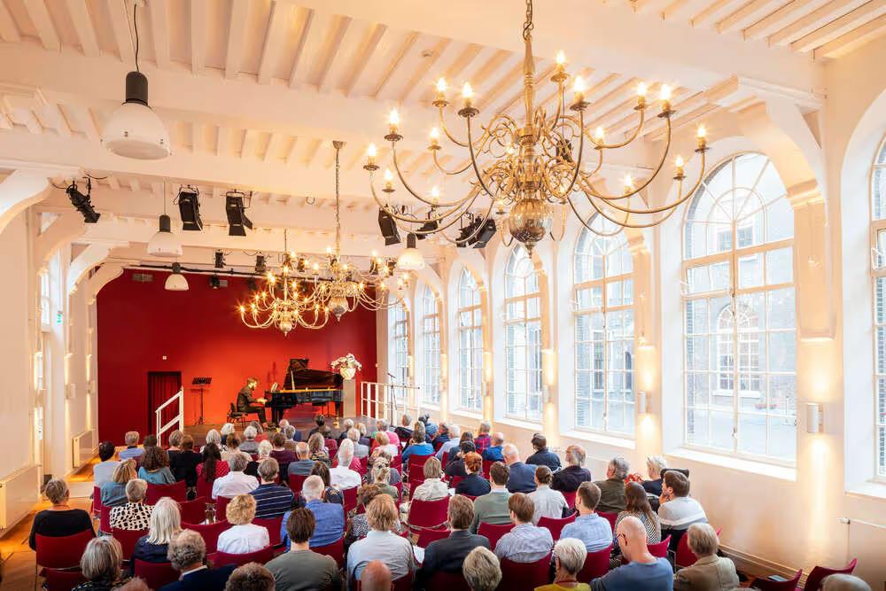 Audience seated in a chandelier-lit hall inside the historic building