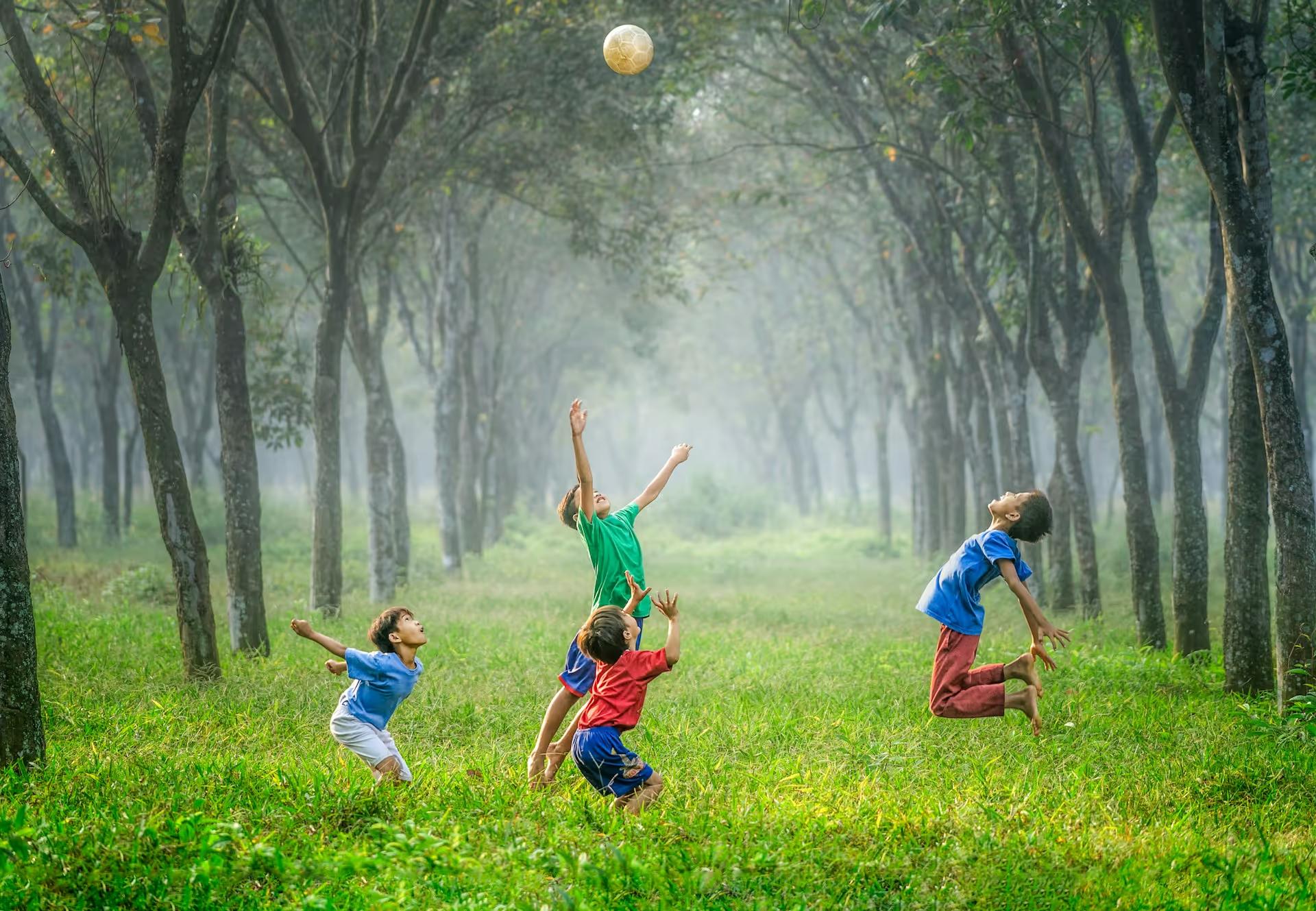 Children jumping and playing ball in a misty forest
