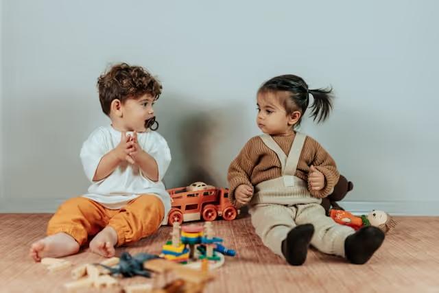 Two toddlers playing with toys on the floor
